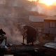 A woman tries to put out a fire on the remains of her burned land in Valparaiso, Chile, on January 2nd, 2017. Image: AP Photo/Luis Hidalgo
